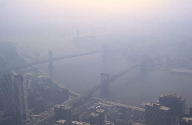 Smog over New York City, with the Brooklyn Bridge and Manhattan skyline visible through haze.