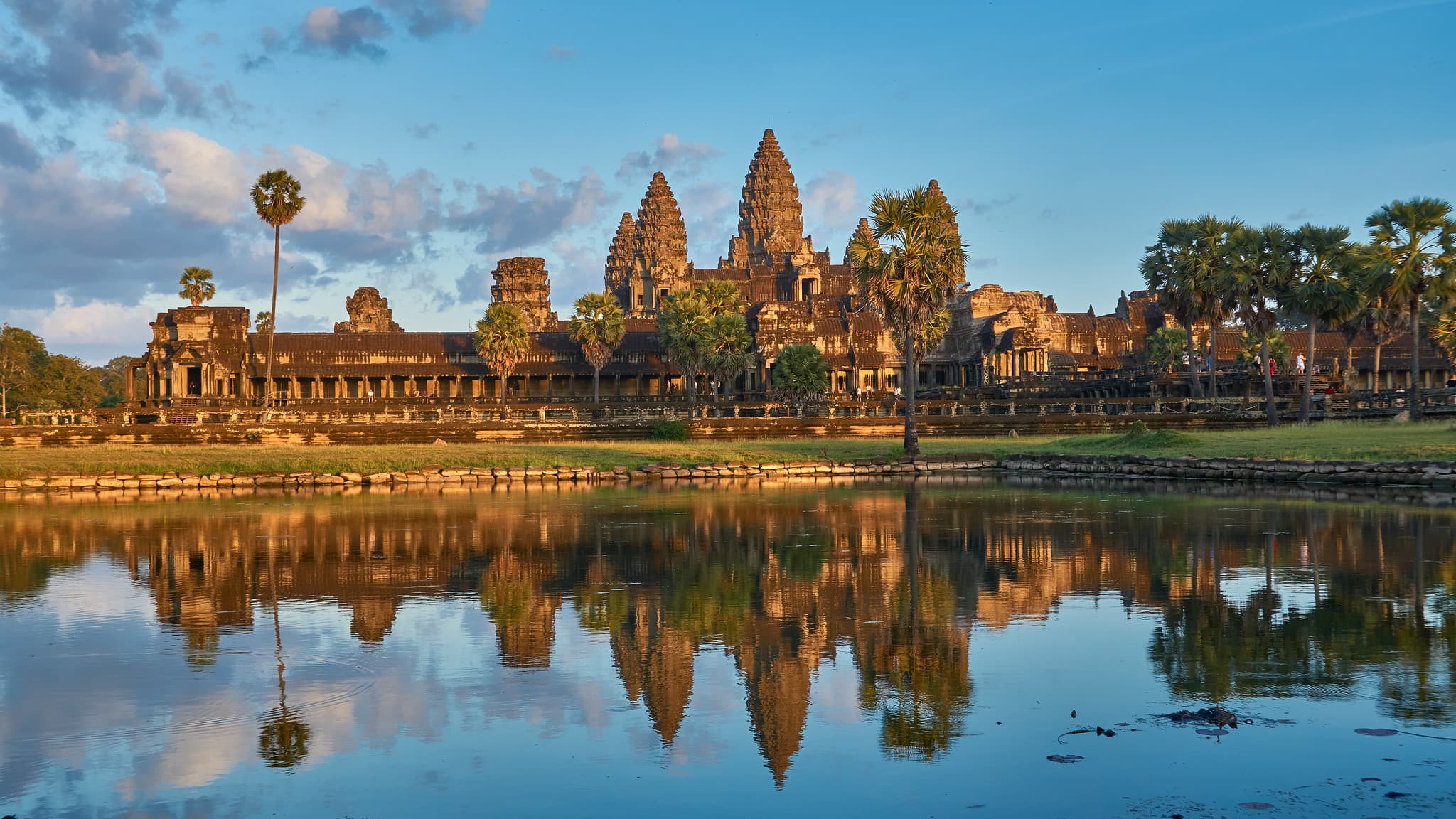 សំណុំប្រាសាទអង្គរវត្តនៅកម្ពុជា មានប្រាង្គខ្ពស់លេចឡើងពីក្រោយទឹក និងផ្លូវថ្ម។