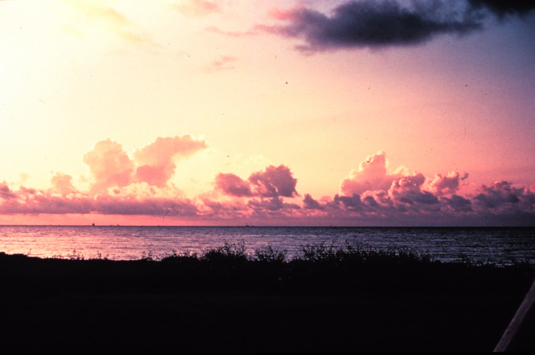 Cumulus clouds building over water with taller clouds in the distance.