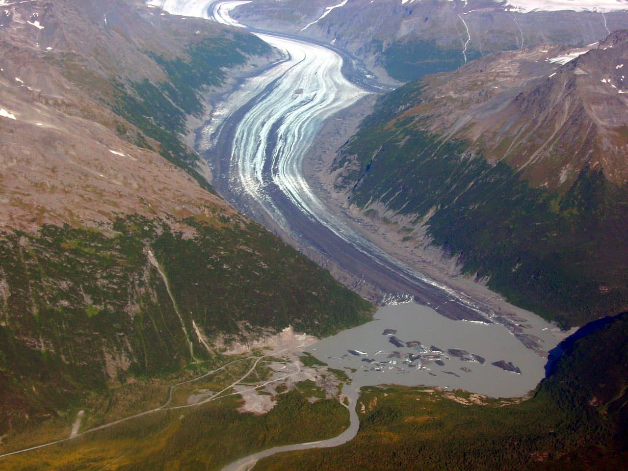 Valdez Glacier in Alaska with blue-white ice, exposed rock, and surrounding mountains.