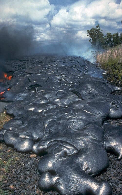 Pahoehoe lava toes advancing across a road in Hawaii.