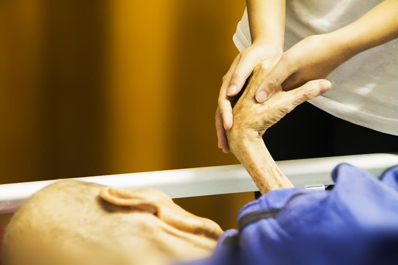 A close view of hands held together during supportive care for serious illness.