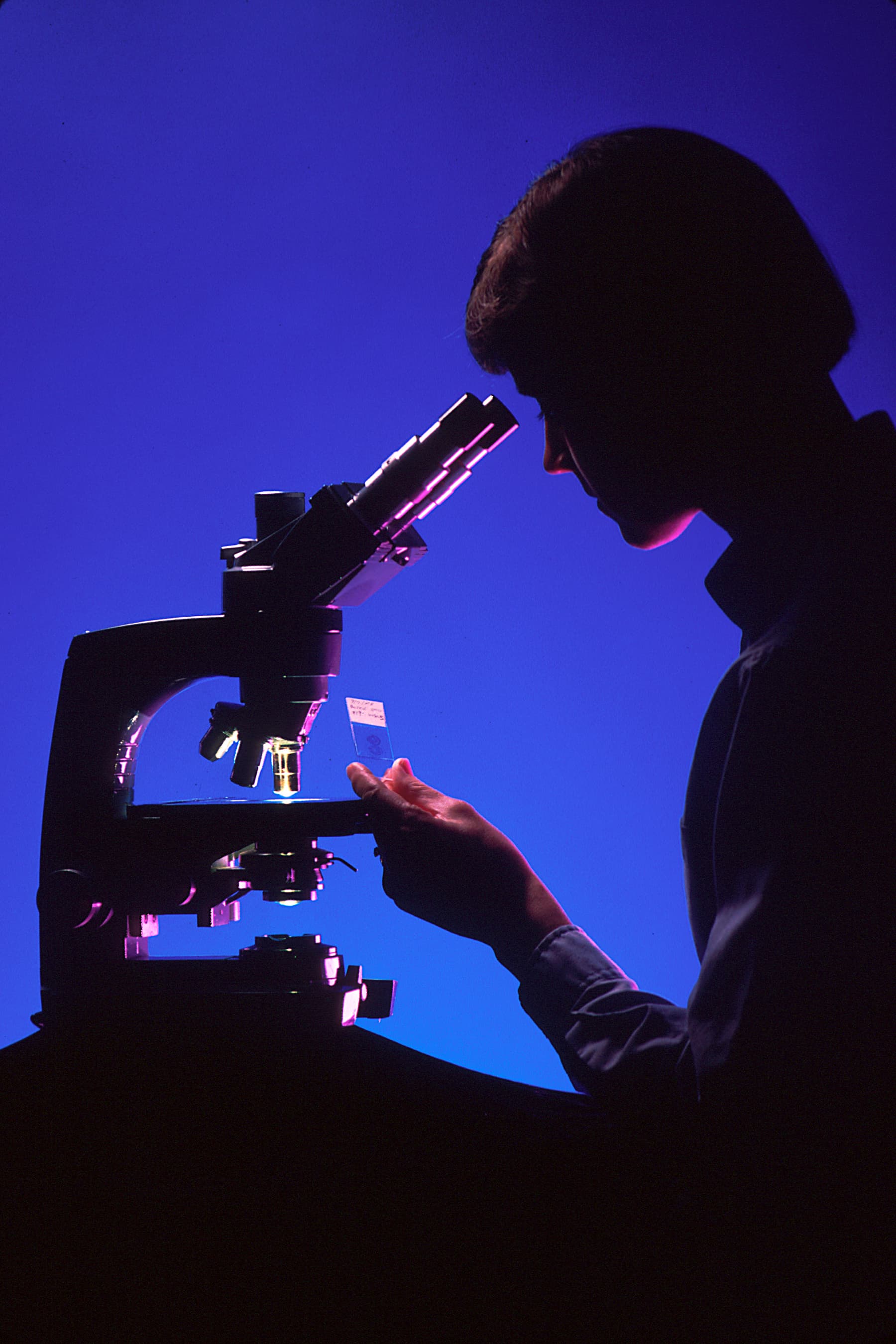 A pathologist working at a microscope in a medical laboratory.