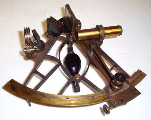 A brass lattice sextant with mirrors, scale, handle, and sighting components.