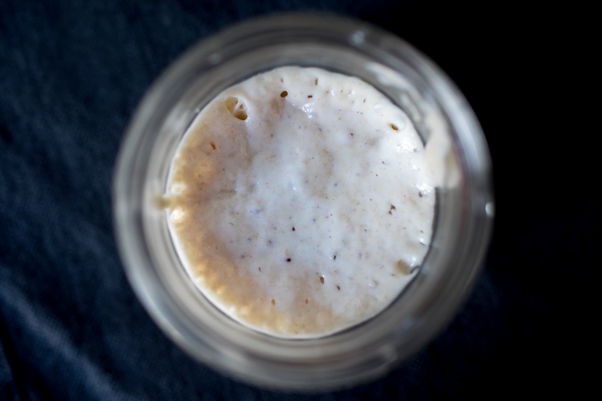Glass jar of bubbly sourdough starter on a kitchen counter
