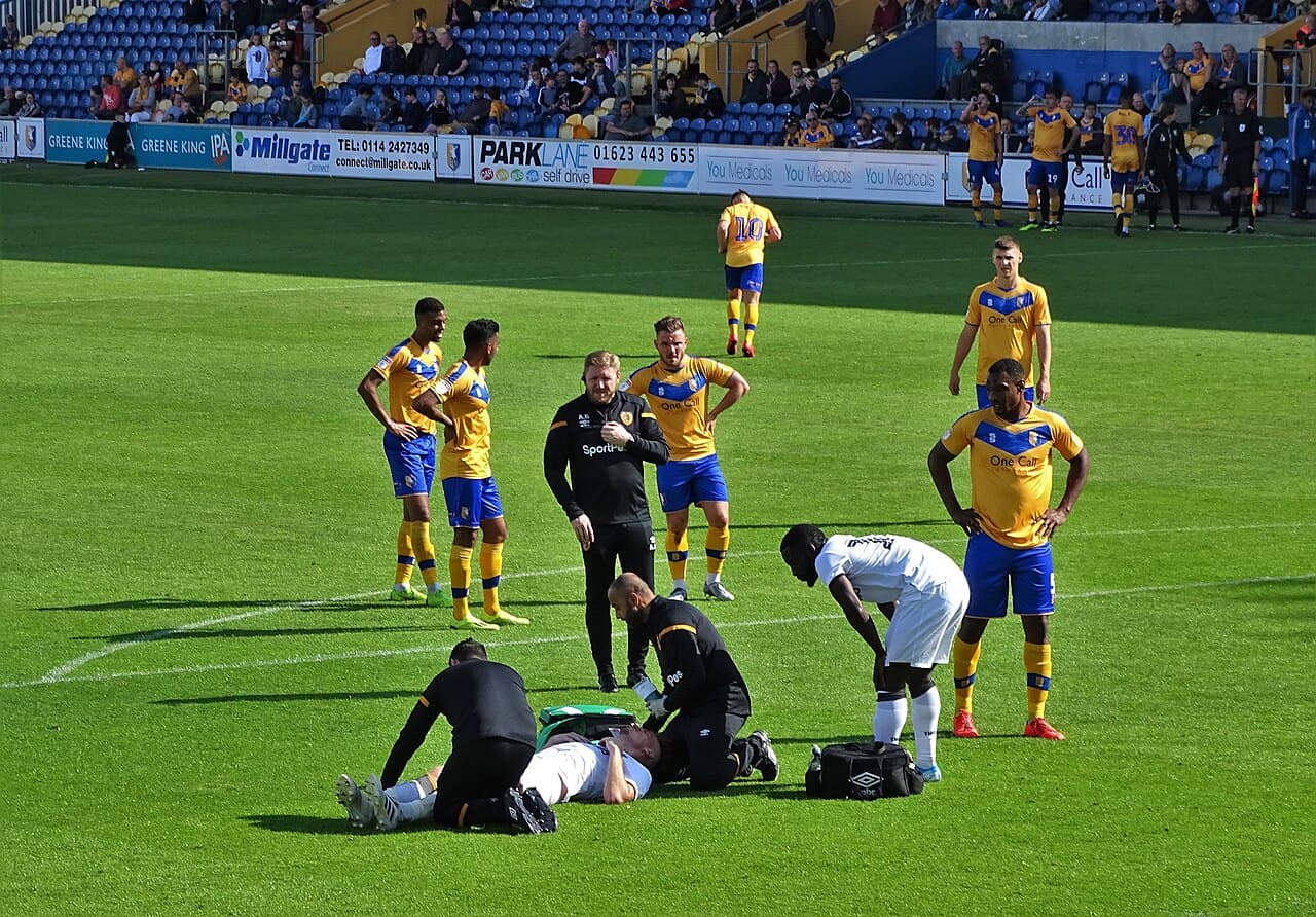 A sports staff member attends to an injured soccer player on the field.