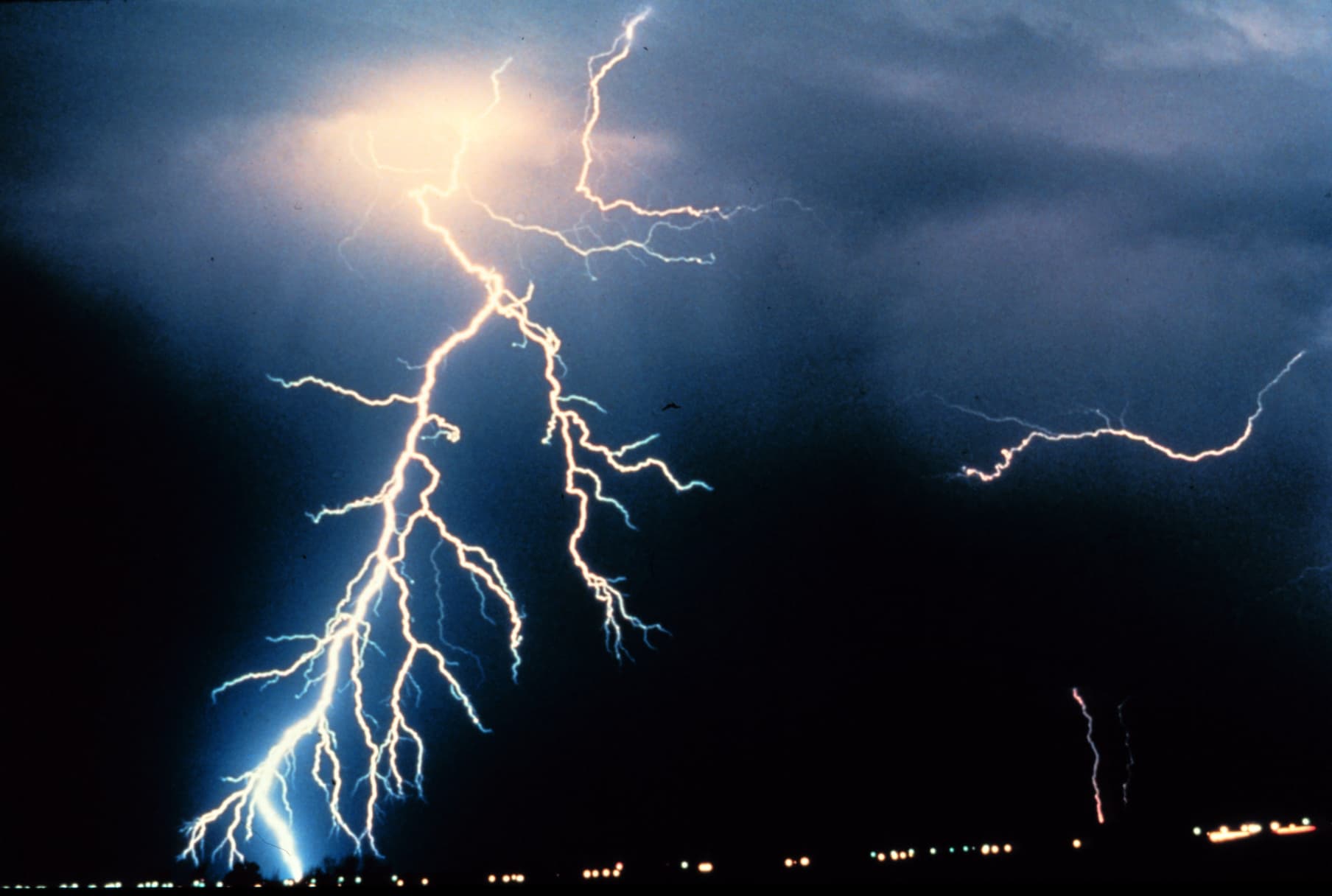 Multiple cloud-to-ground and cloud-to-cloud lightning strokes during a nighttime thunderstorm.